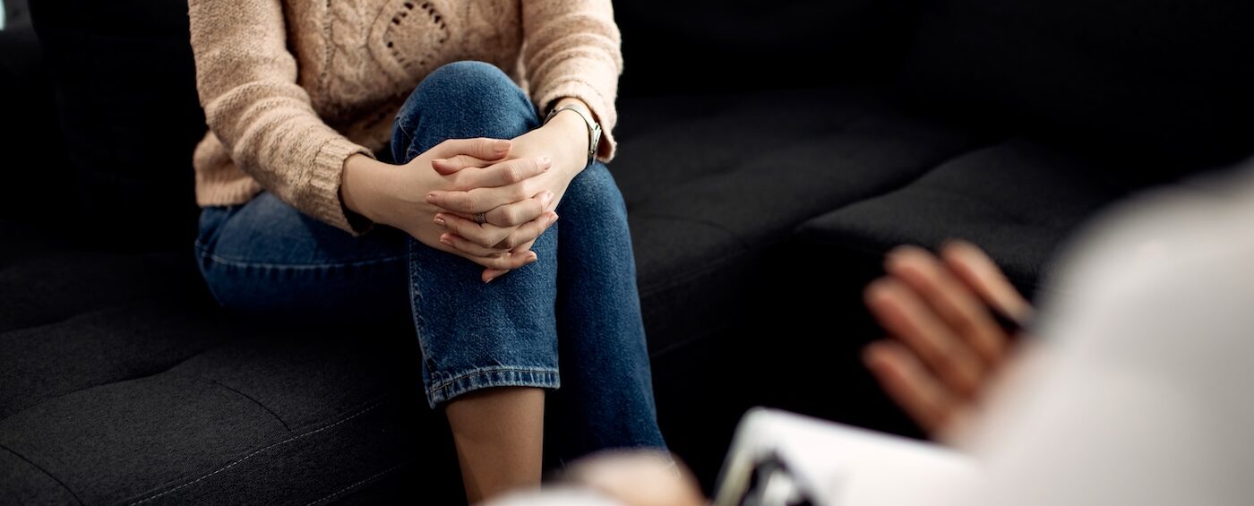 Kobieta na psychoterapii, która siedzi i rozmawia z psychoterapeutką.